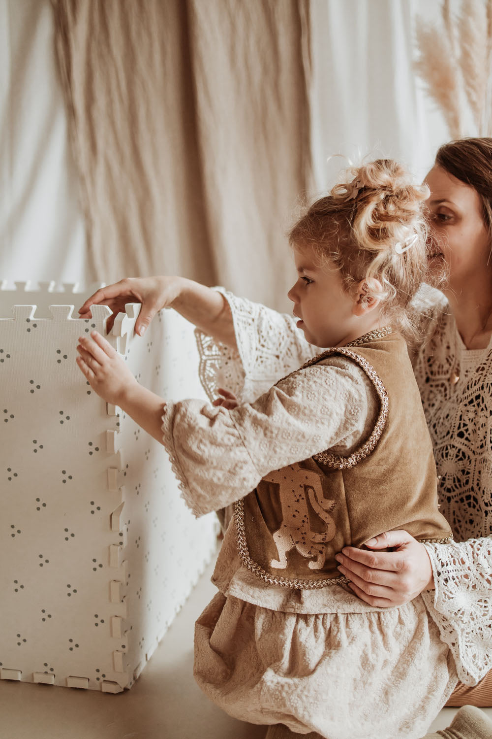 child making a box of the dots puzzlemat, helped by another person