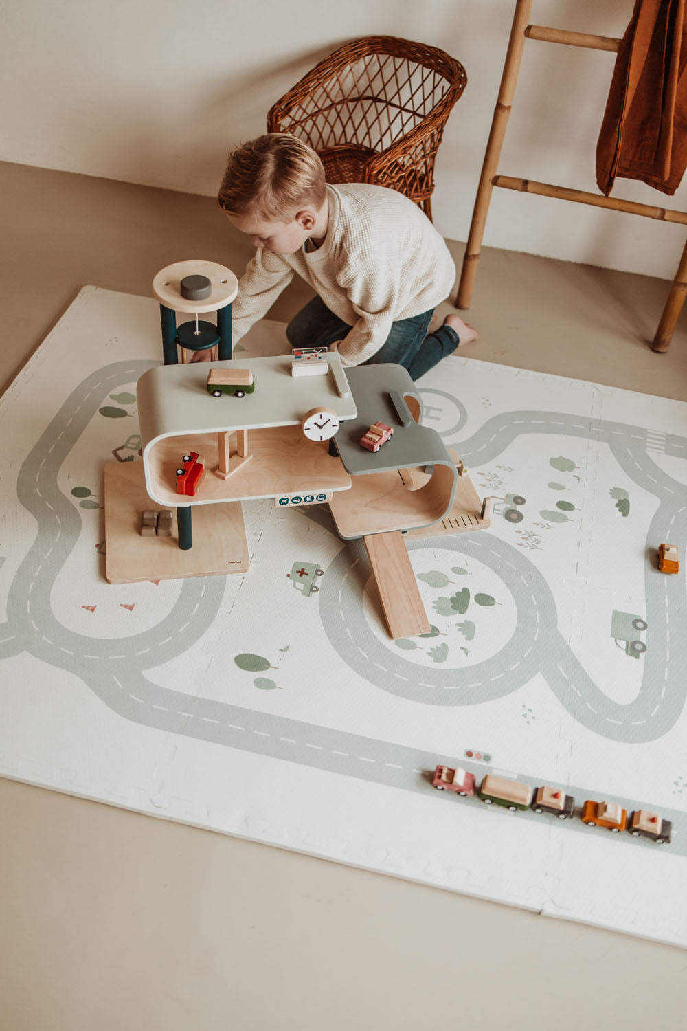 child playing with wooden garage and cars on roadmap puzzlemat