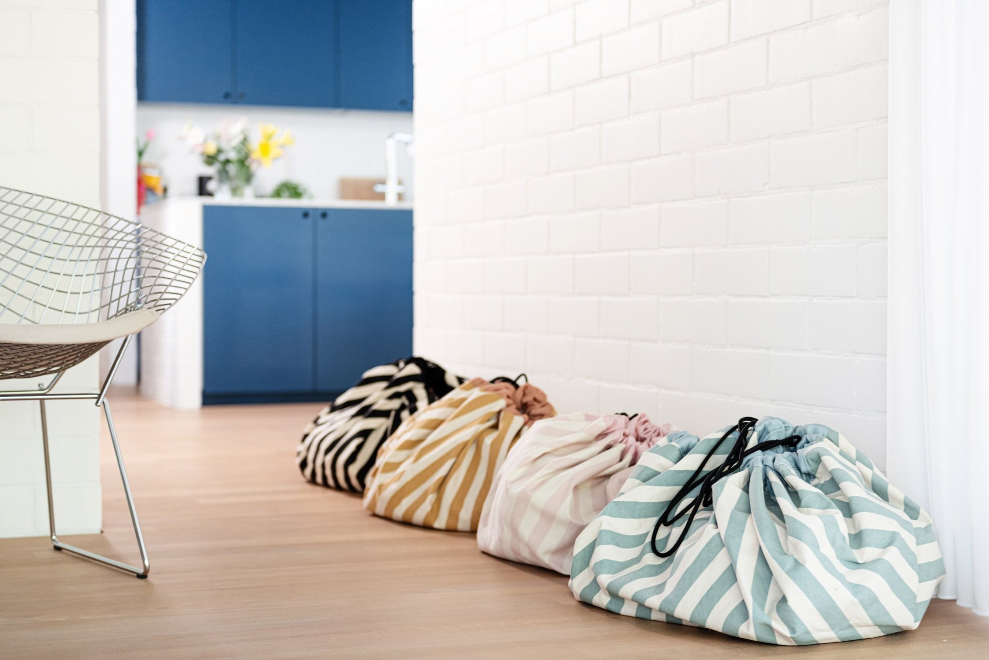 toy storage bag and play mat, cool black, mustard, pink and green stripes, different bags against white wall